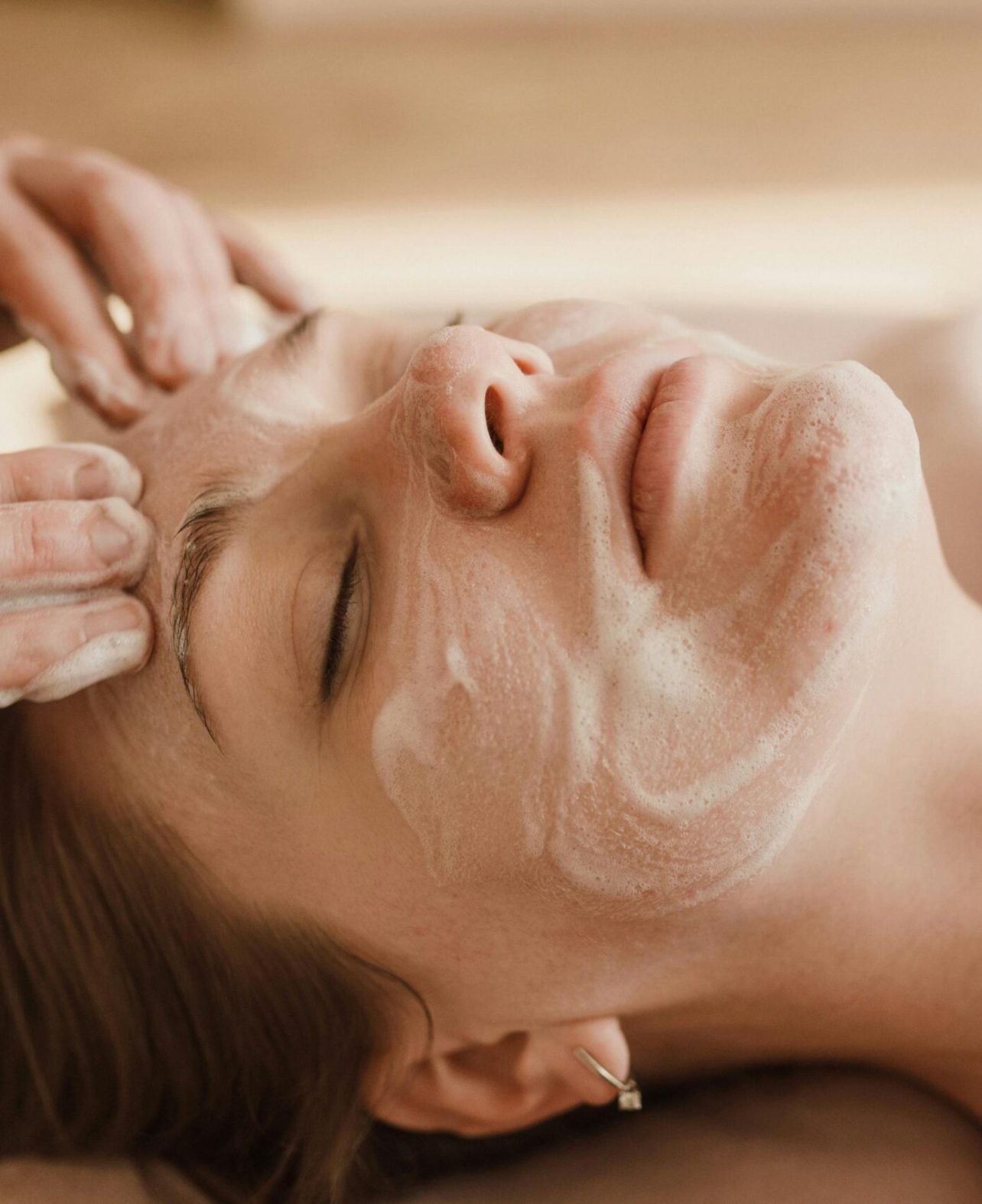 A close-up of a woman receiving a soothing facial massage with a skincare mask.